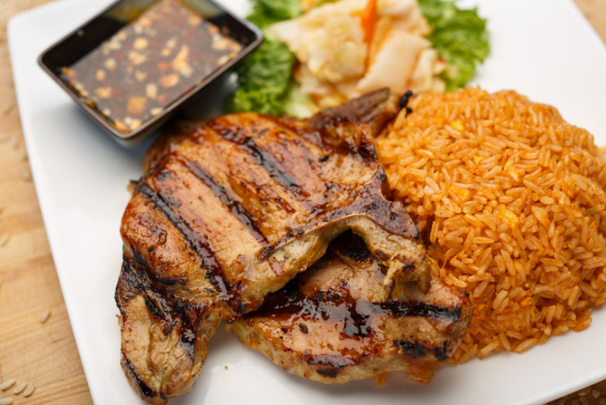 Grilled pork chop with pickled vegetables, fried egg and tomato rice